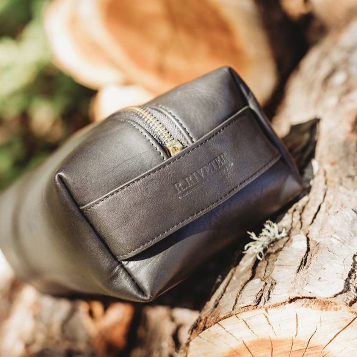 Black leather pouch with gold zipper on a wooden surface