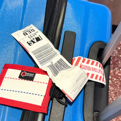 Close-up of a blue suitcase with tags and labels on a textured surface.