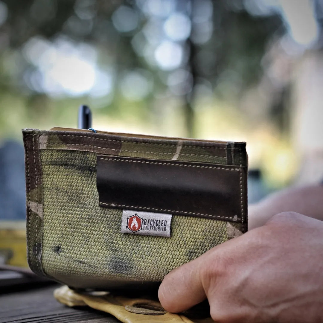 he Inspector recycled firehose notebook cover in Tan and Multicam – held open outdoors showing top-grain leather pen sleeve and Recycled Firefighter badge, handmade in USA