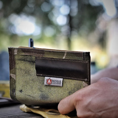 he Inspector recycled firehose notebook cover in Tan and Multicam – held open outdoors showing top-grain leather pen sleeve and Recycled Firefighter badge, handmade in USA